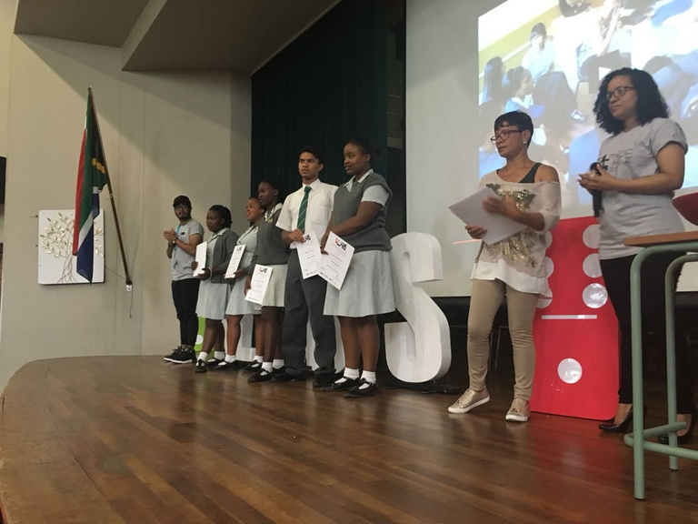 Learners receiving certificates on stage at a school assembly