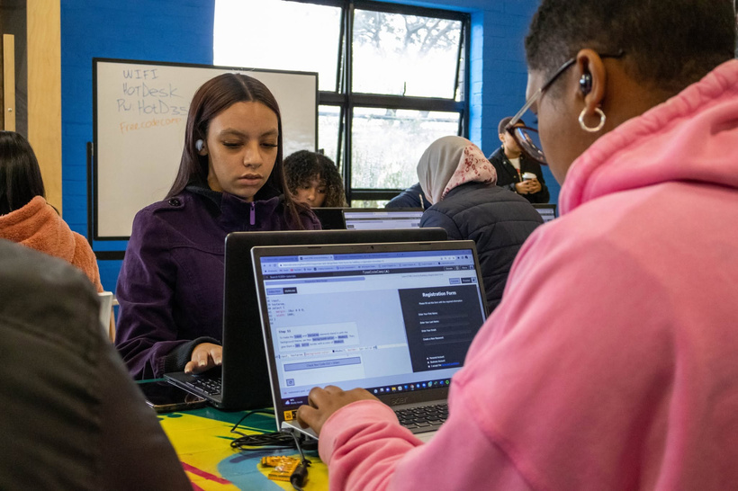 Two learners working on laptops during a coding session